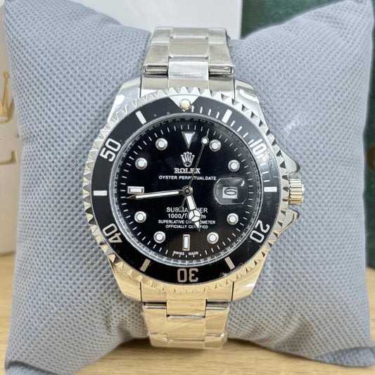 Rolex watch with black dial and silver and gold band on a textured gray surface