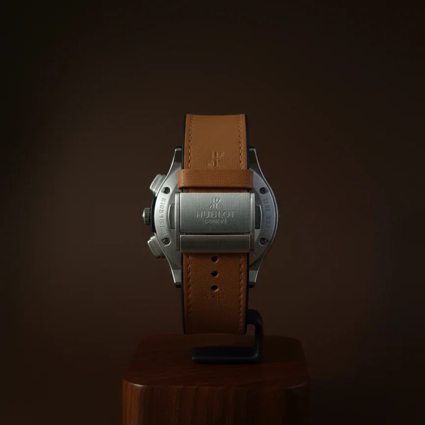 Watch with brown leather strap on a wooden stand against a dark background