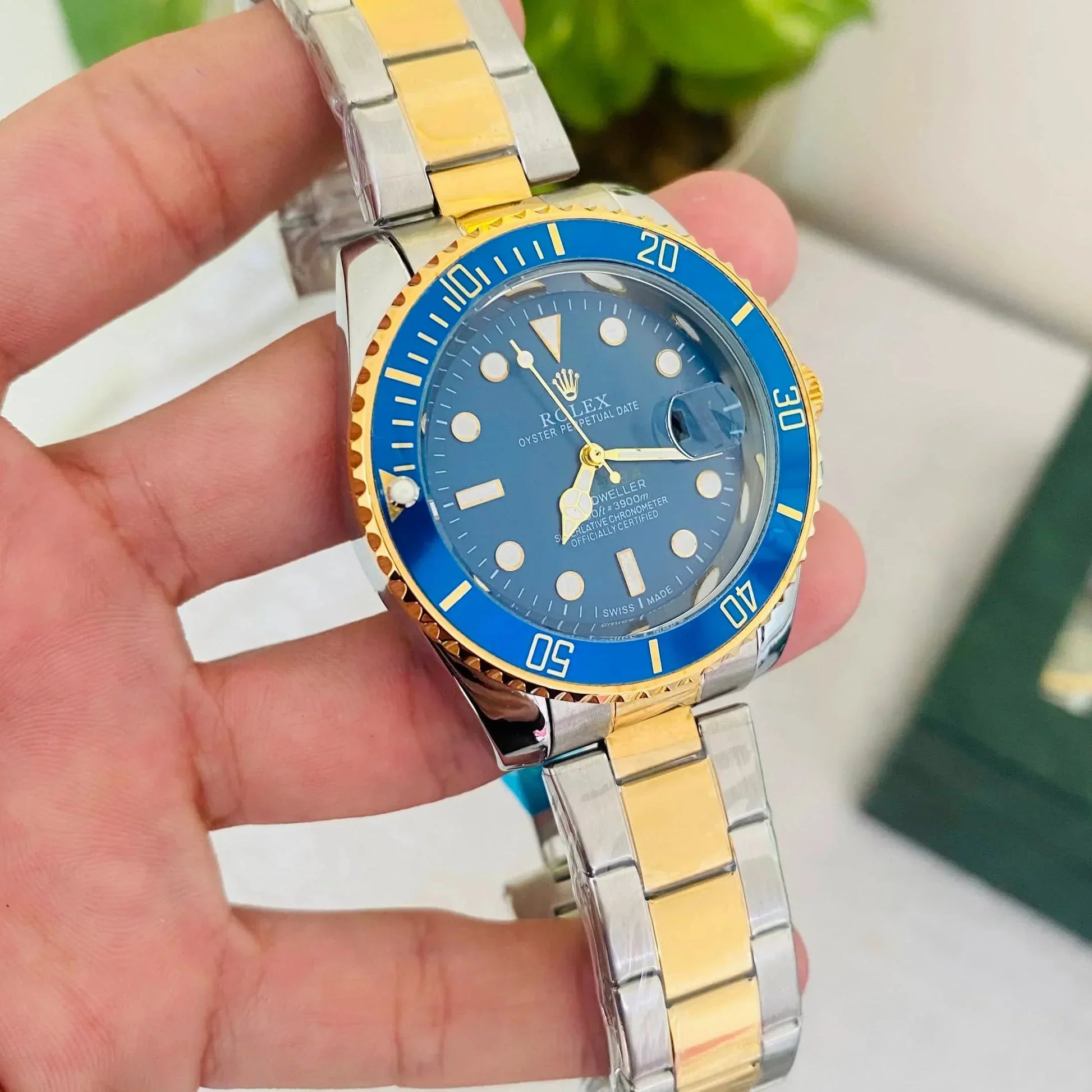 Gold and silver watch with blue dial held in a hand